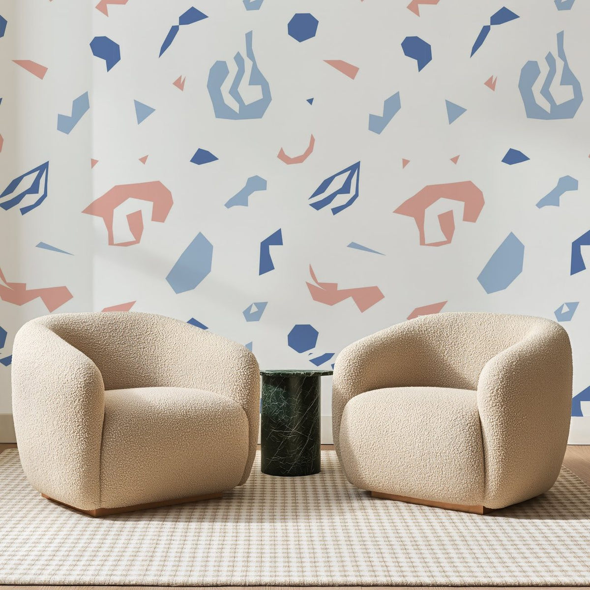 Papier peint panoramique Éclats Géométriques Bleus, posé sur toute la paroi d'un salon, derrière deux fauteuils en bouclette crème et un guéridon en marbre vert