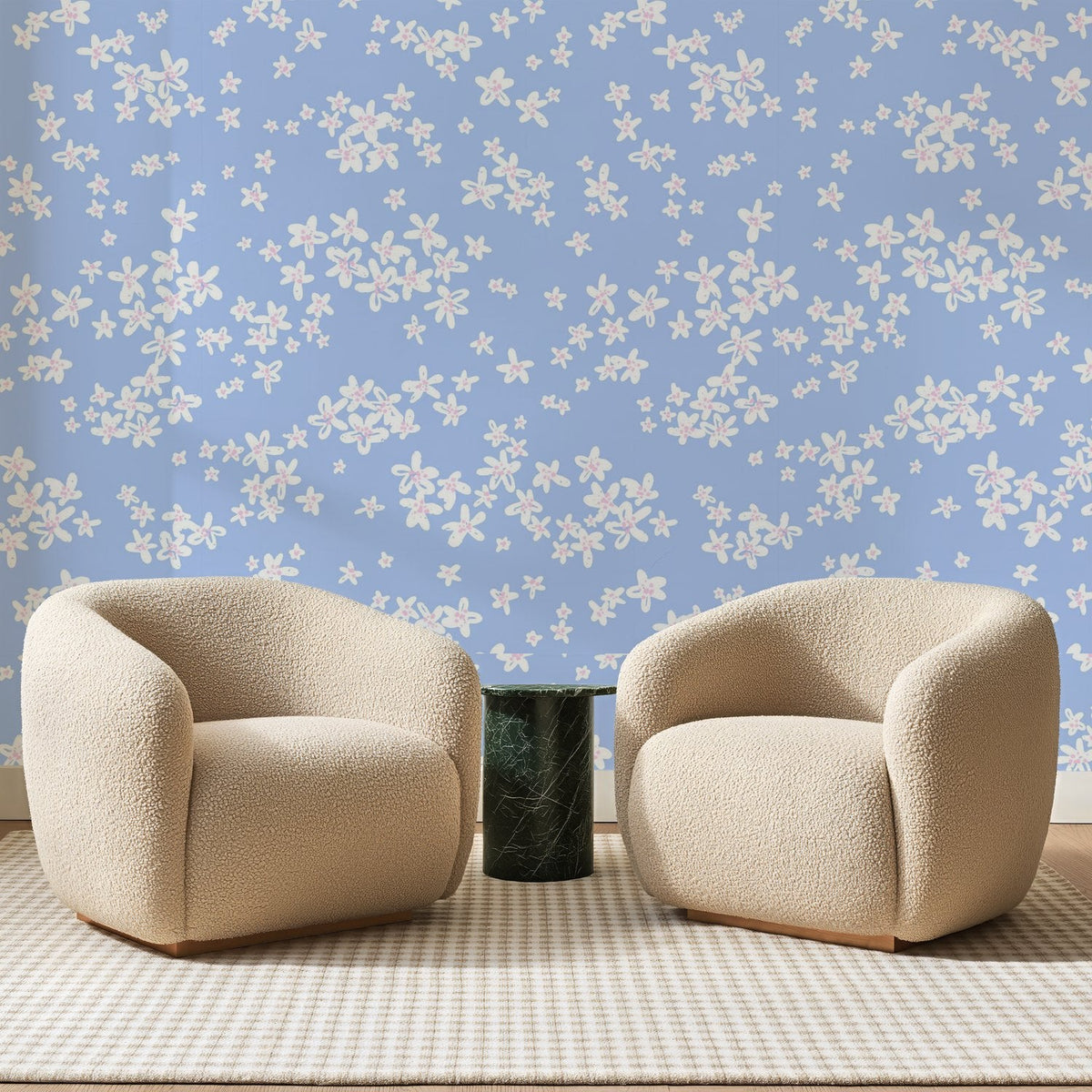 Papier peint panoramique Fleurettes Blanches Bleu Pervenche, posé sur toute la paroi d'un salon, derrière deux fauteuils en bouclette crème et un guéridon en marbre vert
