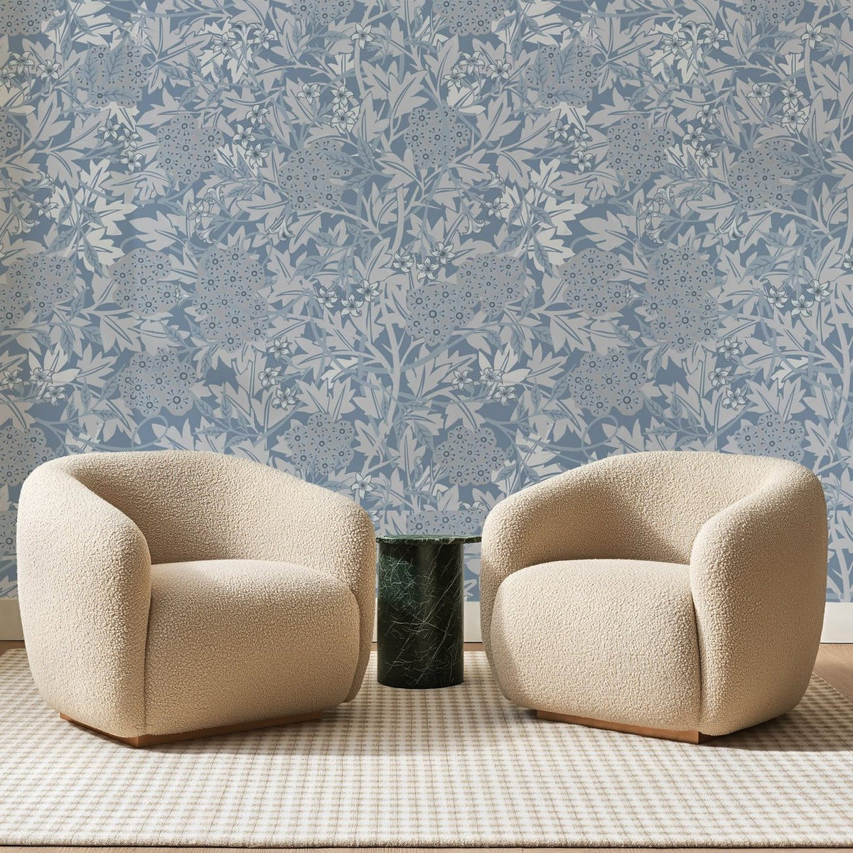 Papier peint panoramique Ramure Fleurie Bleu Ardoise, posé sur toute la paroi d'un salon, derrière deux fauteuils en bouclette crème et un guéridon en marbre vert.