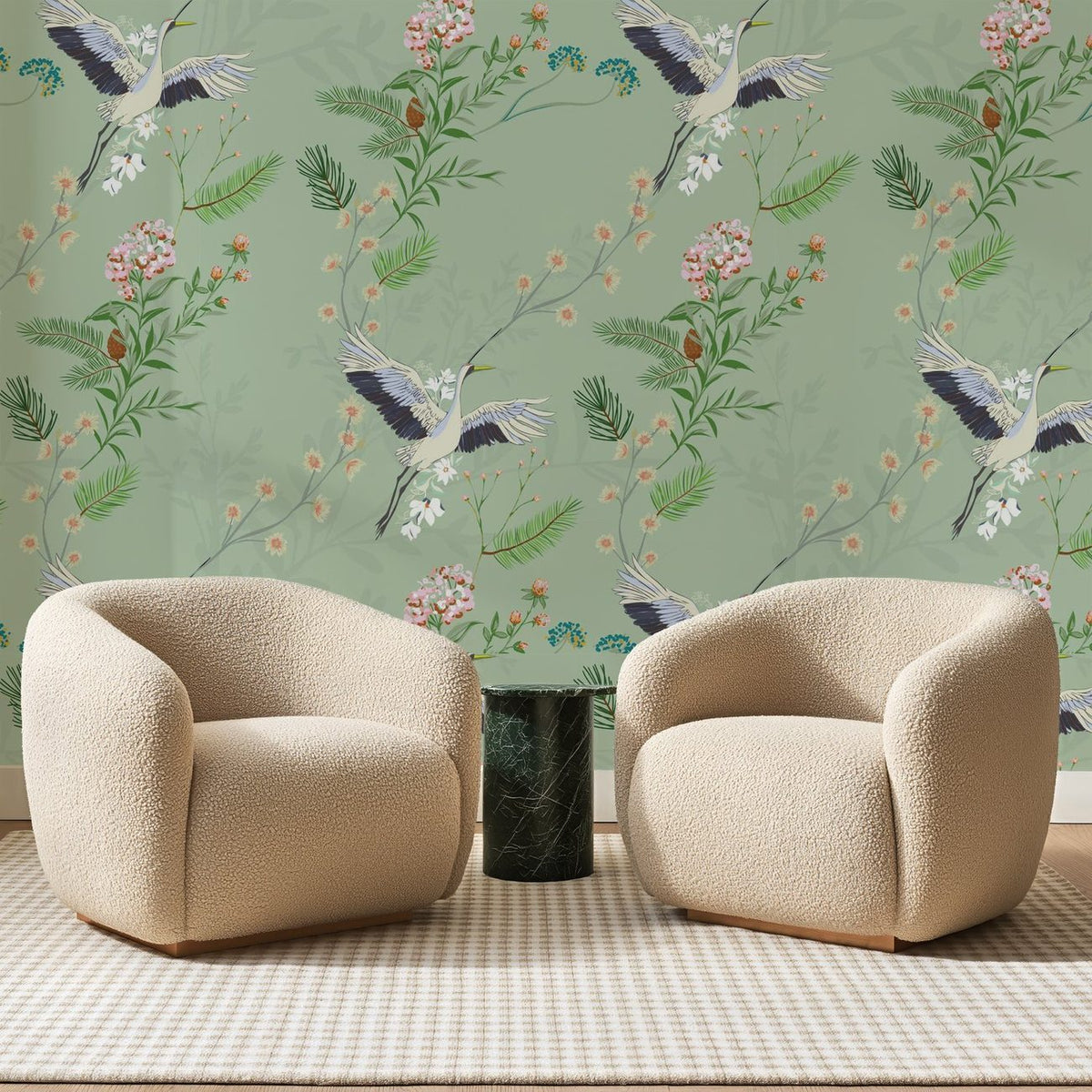 Papier peint panoramique Grues et Pins sur Sauge, posé sur toute la paroi d'un salon, derrière deux fauteuils en bouclette crème et un guéridon en marbre vert