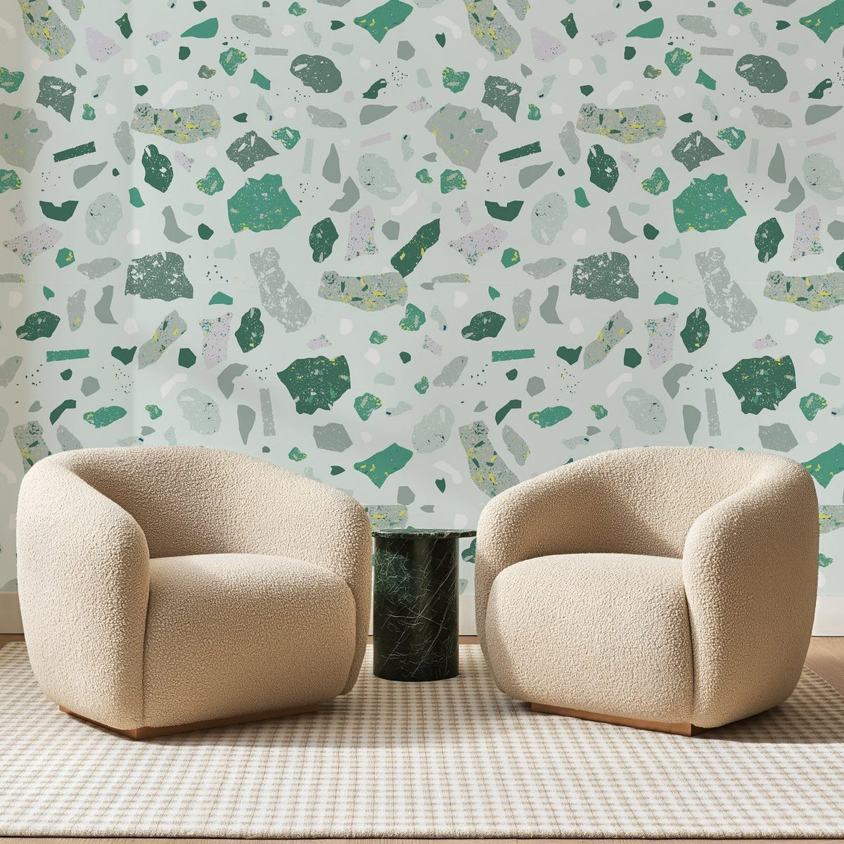 Papier peint panoramique Terrazzo Vert d'Eau, posé sur toute la paroi d'un salon, derrière deux fauteuils en bouclette crème et un guéridon en marbre vert