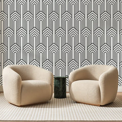Papier peint panoramique Chevrons Art Déco Noirs, posé sur toute la paroi d'un salon, derrière deux fauteuils en bouclette crème et un guéridon en marbre vert