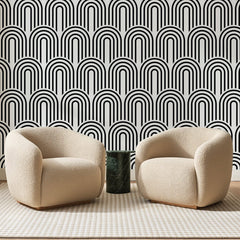 Papier peint panoramique Arcades Art Déco Noires, posé sur toute la paroi d'un salon, derrière deux fauteuils en bouclette crème et un guéridon en marbre vert
