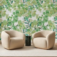 Papier peint panoramique Feuillage d'Eucalyptus Vert Pomme, posé sur toute la paroi d'un salon, derrière deux fauteuils en bouclette crème et un guéridon en marbre vert