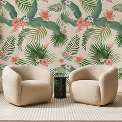 Papier peint panoramique Palmes et Hibiscus Corail, posé sur toute la paroi d'un salon, derrière deux fauteuils en bouclette crème et un guéridon en marbre vert