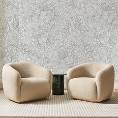 Papier peint panoramique Pivoines au Trait Gris, posé sur toute la paroi d'un salon, derrière deux fauteuils en bouclette crème et un guéridon en marbre vert