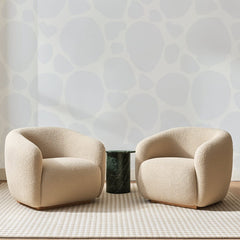 Papier peint panoramique Galets Gris Perle, posé sur toute la paroi d'un salon, derrière deux fauteuils en bouclette crème et un guéridon en marbre vert