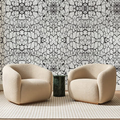 Papier peint panoramique Craquelures Noires sur Blanc, posé sur toute la paroi d'un salon, derrière deux fauteuils en bouclette crème et un guéridon en marbre vert