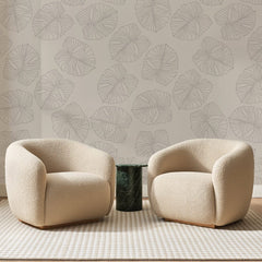 Papier peint panoramique Grandes Feuilles au Trait Greige, posé sur toute la paroi d'un salon, derrière deux fauteuils en bouclette crème et un guéridon en marbre vert