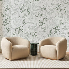 Papier peint panoramique Semis de Rameaux Vert Amande, posé sur toute la paroi d'un salon, derrière deux fauteuils en bouclette crème et un guéridon en marbre vert
