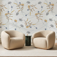 Papier peint panoramique Semis de Chardons Dorés, posé sur toute la paroi d'un salon, derrière deux fauteuils en bouclette crème et un guéridon en marbre vert
