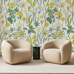 Papier peint panoramique Pissenlits et Ombelles Jaunes, posé sur toute la paroi d'un salon, derrière deux fauteuils en bouclette crème et un guéridon en marbre vert