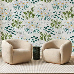 Papier peint panoramique Prairie de Marguerites Vert Sapin, posé sur toute la paroi d'un salon, derrière deux fauteuils en bouclette crème et un guéridon en marbre vert