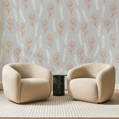 Papier peint panoramique Tulipes Terracotta sur Gris Perle, posé sur toute la paroi d'un salon, derrière deux fauteuils en bouclette crème et un guéridon en marbre vert