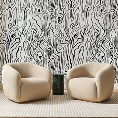 Papier peint panoramique Veinures de Bois Noires, posé sur toute la paroi d'un salon, derrière deux fauteuils en bouclette crème et un guéridon en marbre vert