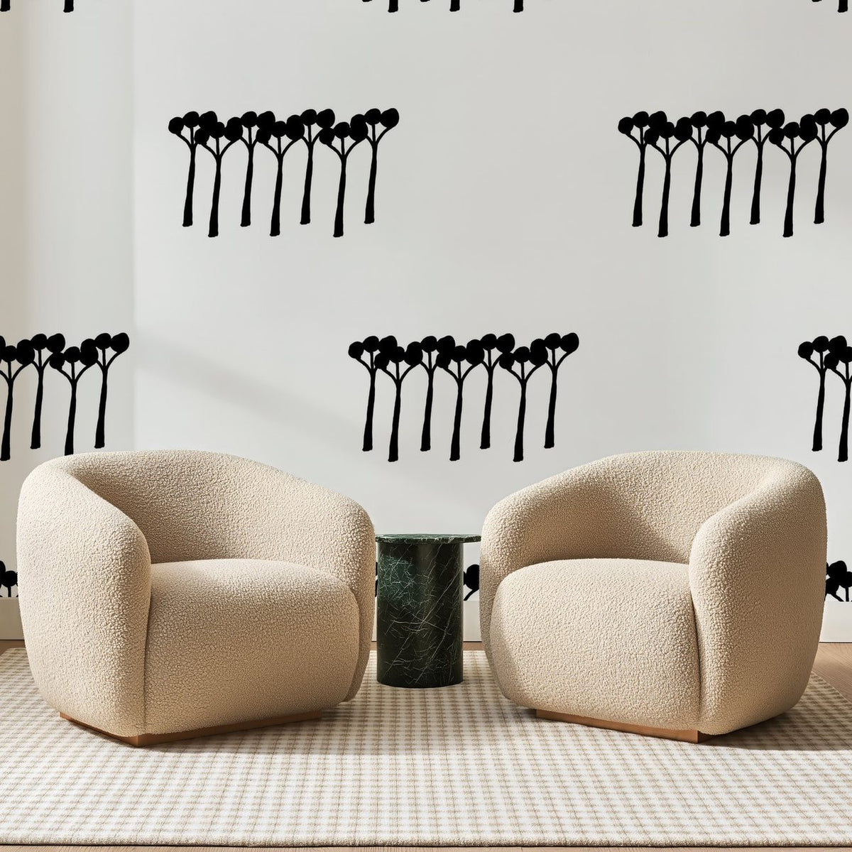 Papier peint panoramique Rangées d'Arbres Noirs, posé sur toute la paroi d'un salon, derrière deux fauteuils en bouclette crème et un guéridon en marbre vert