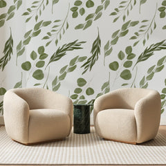 Papier peint panoramique Branches d'Eucalyptus Sauge, posé sur toute la paroi d'un salon, derrière deux fauteuils en bouclette crème et un guéridon en marbre vert