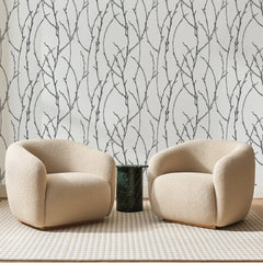 Papier peint panoramique Rameaux Gris Argent, posé sur toute la paroi d'un salon, derrière deux fauteuils en bouclette crème et un guéridon en marbre vert