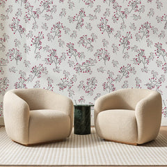 Papier peint panoramique Brindilles à Baies Framboise, posé sur toute la paroi d'un salon, derrière deux fauteuils en bouclette crème et un guéridon en marbre vert