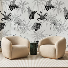 Papier peint panoramique Palmes d'Encre Noire, posé sur toute la paroi d'un salon, derrière deux fauteuils en bouclette crème et un guéridon en marbre vert