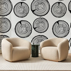 Papier peint panoramique Cernes de Bois Noirs, posé sur toute la paroi d'un salon, derrière deux fauteuils en bouclette crème et un guéridon en marbre vert