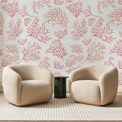 Papier peint panoramique Branches de Corail Rose, posé sur toute la paroi d'un salon, derrière deux fauteuils en bouclette crème et un guéridon en marbre vert