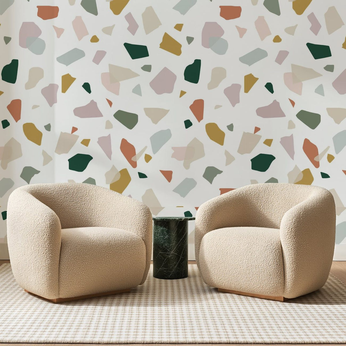Papier peint panoramique Terrazzo Crème et Ocre, posé sur toute la paroi d'un salon, derrière deux fauteuils en bouclette crème et un guéridon en marbre vert