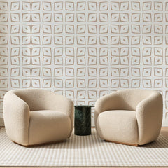 Papier peint panoramique Grille de Losanges Camel, posé sur toute la paroi d'un salon, derrière deux fauteuils en bouclette crème et un guéridon en marbre vert