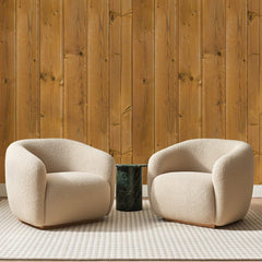 Papier peint panoramique Lambris de Pin Miel, posé sur toute la paroi d'un salon, derrière deux fauteuils en bouclette crème et un guéridon en marbre vert
