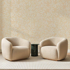 Papier peint panoramique Brindilles Blanches sur Abricot, posé sur toute la paroi d'un salon, derrière deux fauteuils en bouclette crème et un guéridon en marbre vert