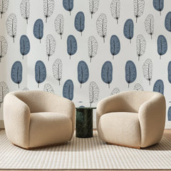 Papier peint panoramique Plumes Scandinaves Bleu Ardoise, posé sur toute la paroi d'un salon, derrière deux fauteuils en bouclette crème et un guéridon en marbre vert