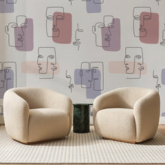 Papier peint panoramique Visages au Trait Mauve, posé sur toute la paroi d'un salon, derrière deux fauteuils en bouclette crème et un guéridon en marbre vert