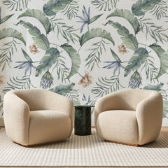 Papier peint panoramique Palmes Aquarelle Vert Pâle, posé sur toute la paroi d'un salon, derrière deux fauteuils en bouclette crème et un guéridon en marbre vert