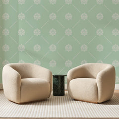 Papier peint panoramique Semis de Médaillons Sauge, posé sur toute la paroi d'un salon, derrière deux fauteuils en bouclette crème et un guéridon en marbre vert