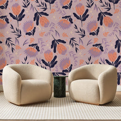 Papier peint panoramique Protéas Corail sur Mauve, posé sur toute la paroi d'un salon, derrière deux fauteuils en bouclette crème et un guéridon en marbre vert