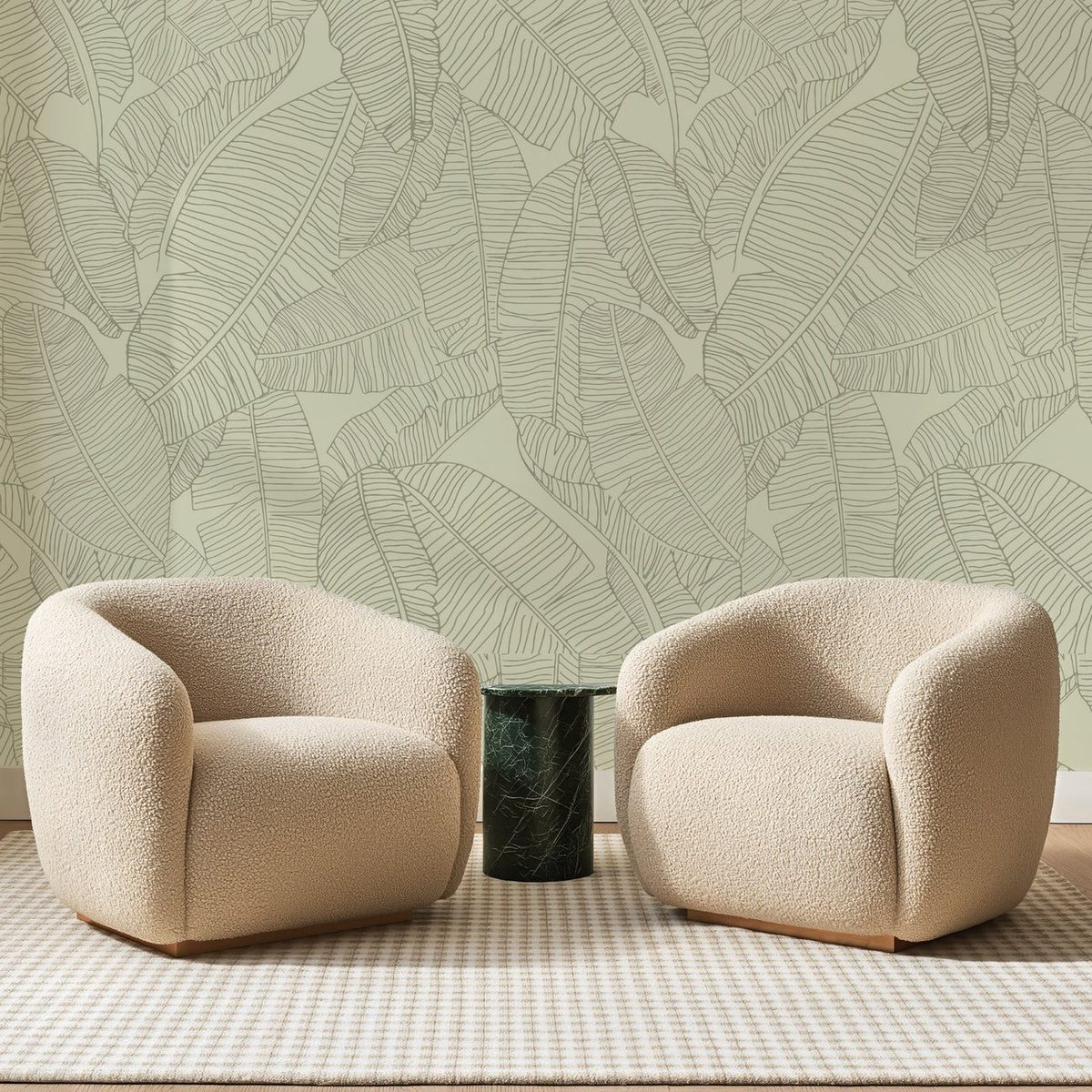 Papier peint panoramique Bananiers au Trait Vert Pâle, posé sur toute la paroi d'un salon, derrière deux fauteuils en bouclette crème et un guéridon en marbre vert