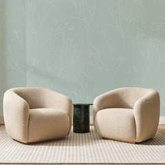 Papier peint panoramique Brindilles Blanches sur Vert d'Eau, posé sur toute la paroi d'un salon, derrière deux fauteuils en bouclette crème et un guéridon en marbre vert