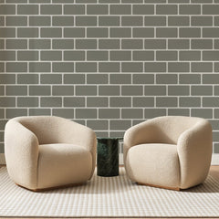 Papier peint panoramique Briques Industrielles Kaki, posé sur toute la paroi d'un salon, derrière deux fauteuils en bouclette crème et un guéridon en marbre vert