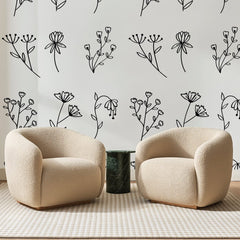 Papier peint panoramique Fleurs des Champs à l'Encre, posé sur toute la paroi d'un salon, derrière deux fauteuils en bouclette crème et un guéridon en marbre vert
