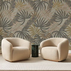 Papier peint panoramique Palmes Graphiques Ocre, posé sur toute la paroi d'un salon, derrière deux fauteuils en bouclette crème et un guéridon en marbre vert
