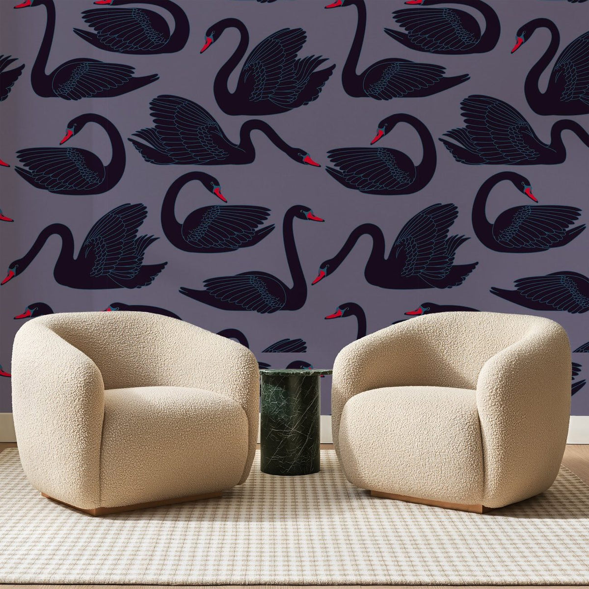 Papier peint panoramique Cygnes Noirs sur Mauve, posé sur toute la paroi d'un salon, derrière deux fauteuils en bouclette crème et un guéridon en marbre vert