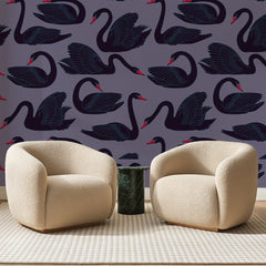 Papier peint panoramique Cygnes Noirs sur Mauve, posé sur toute la paroi d'un salon, derrière deux fauteuils en bouclette crème et un guéridon en marbre vert