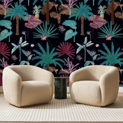 Papier peint panoramique Jungle Nocturne Rose Et Turquoise, posé sur toute la paroi d'un salon, derrière deux fauteuils en bouclette crème et un guéridon en marbre vert