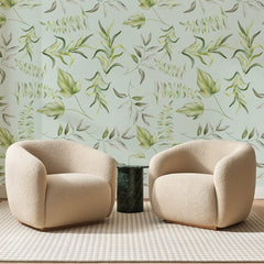 Papier peint panoramique Feuillages Aquarelle Vert d'Eau, posé sur toute la paroi d'un salon, derrière deux fauteuils en bouclette crème et un guéridon en marbre vert