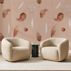 Papier peint panoramique Plumes de Pampa Rosé, posé sur toute la paroi d'un salon, derrière deux fauteuils en bouclette crème et un guéridon en marbre vert