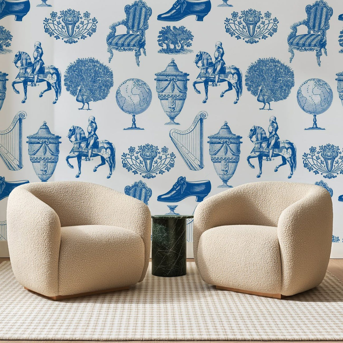Papier peint panoramique Cabinet de Curiosités Bleu Roi, posé sur toute la paroi d'un salon, derrière deux fauteuils en bouclette crème et un guéridon en marbre vert