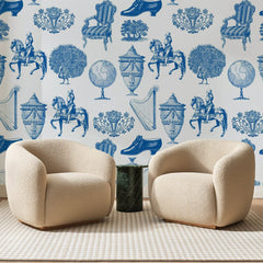 Papier peint panoramique Cabinet de Curiosités Bleu Roi, posé sur toute la paroi d'un salon, derrière deux fauteuils en bouclette crème et un guéridon en marbre vert