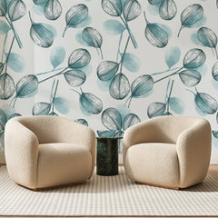 Papier peint panoramique Eucalyptus à l'Encre Bleue, posé sur toute la paroi d'un salon, derrière deux fauteuils en bouclette crème et un guéridon en marbre vert.