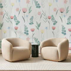 Papier peint panoramique Semis Aquarellé Rose et Sauge, posé sur toute la paroi d'un salon, derrière deux fauteuils en bouclette crème et un guéridon en marbre vert