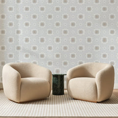 Papier peint panoramique Petites Rosaces Gris Perle, posé sur toute la paroi d'un salon, derrière deux fauteuils en bouclette crème et un guéridon en marbre vert